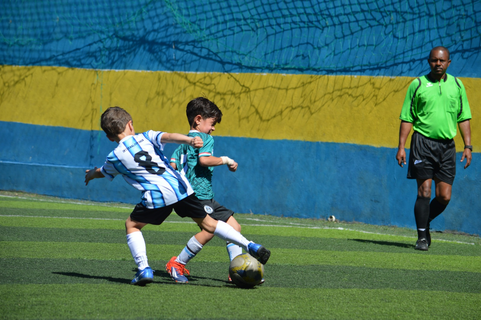 Crianças disputando a bola durante jogo