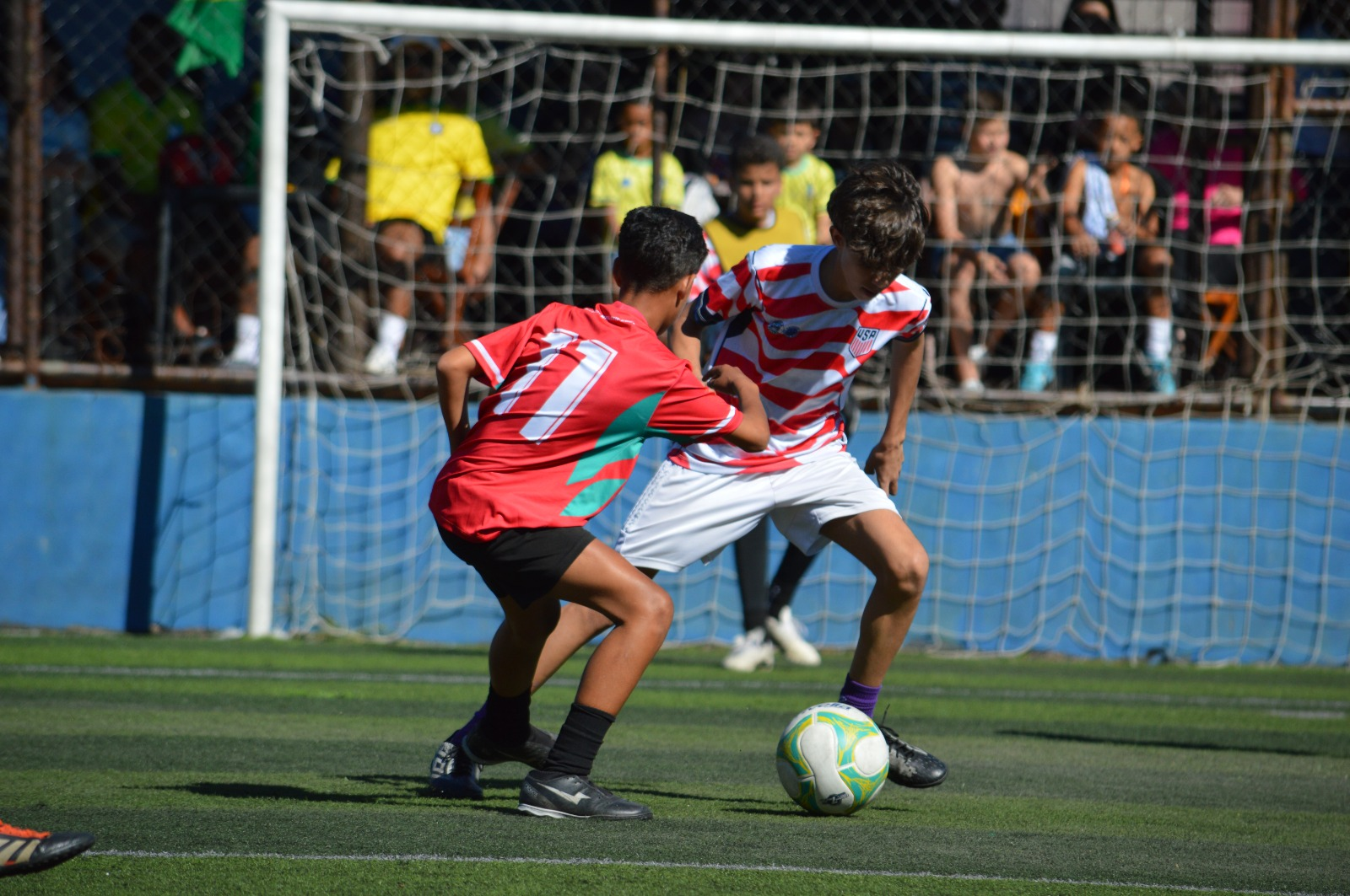 Jogadores juvenis disputando a bola em frente ao gol