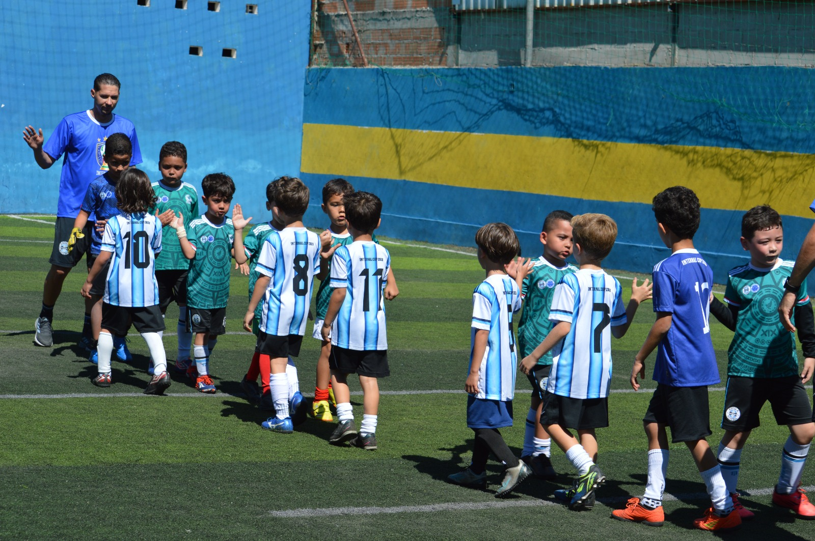 Crianças se cumprimentando em campo durante atividade da CJR Esportes